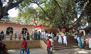 Students eagerly gather outside the historic religious building, surrounded by lush trees. Some enthusiastic travelers ascend the steps, while others chat or rest nearby. The lively scene buzzes with youthful excitement, making it an ideal travel experience for students.